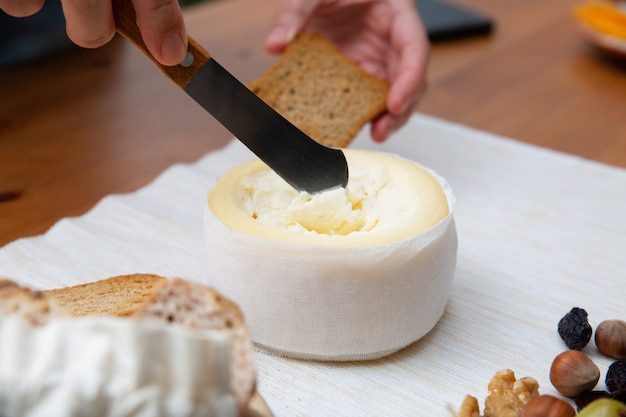 Hand taking soft cheese with knife to spread on bread