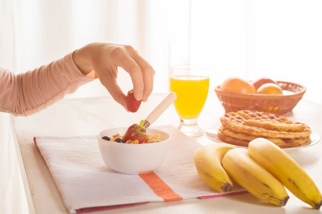 Hand taking strawberry for breakfast