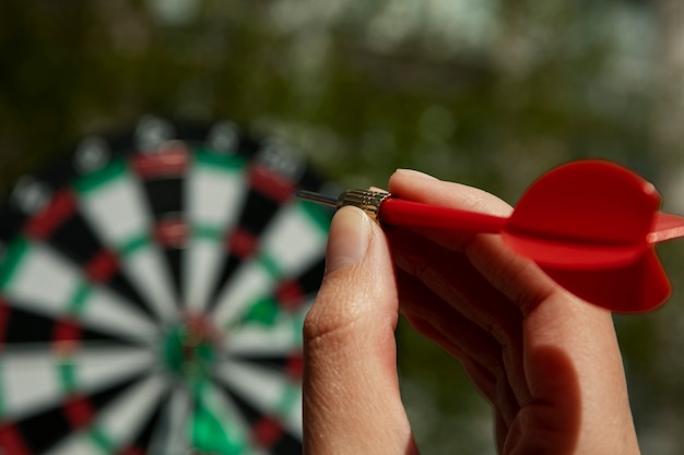 Free photo hand throwing dart arrow at board