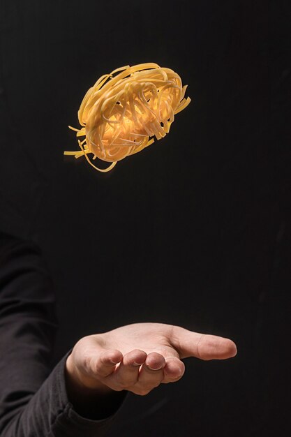 Hand throwing pasta up in the air