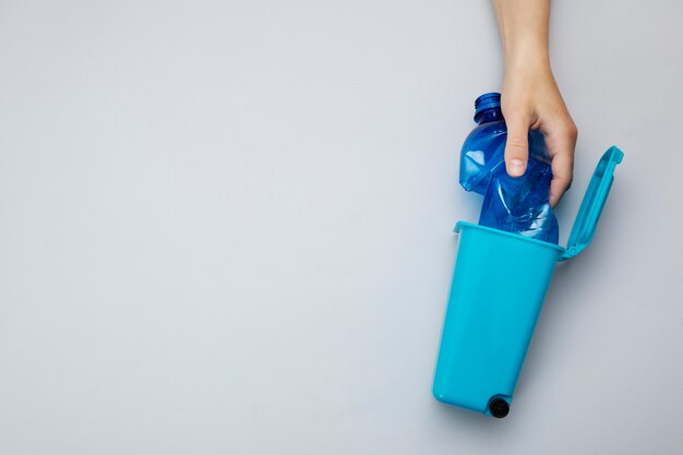 Hand throwing plastic bottle in bin top view