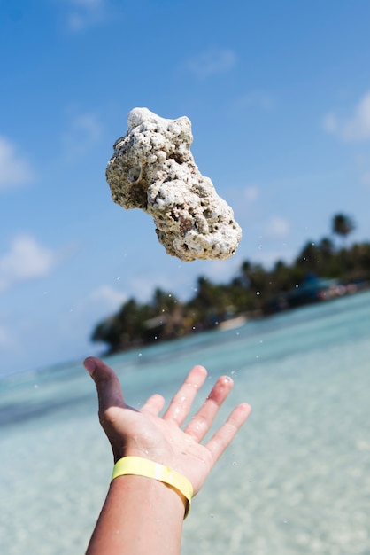 Hand throwing rock at the seaside