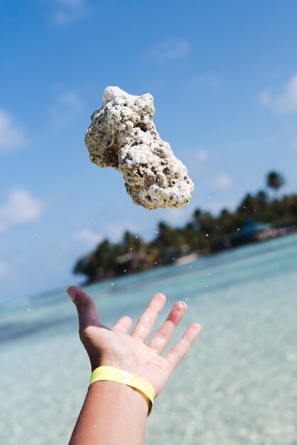 海辺で岩を投げている手