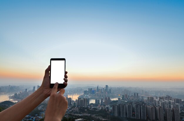 Hand touching a mobile screen with city background