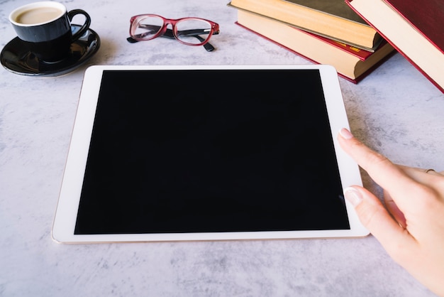 Hand touching tablet on a desk