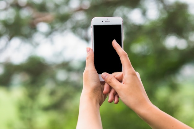 Бесплатное фото Рука, касающаяся экрана мобильного телефона на открытом воздухе