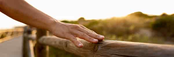 Free photo hand touching wooden fence outdoors