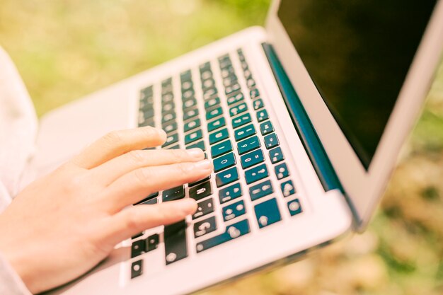 Hand typing on laptop in nature