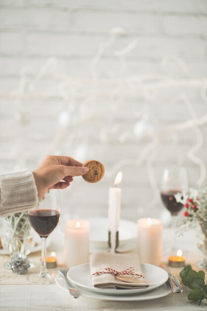 Hand of unrecognizable woman holding cookie above Christmas dinner table