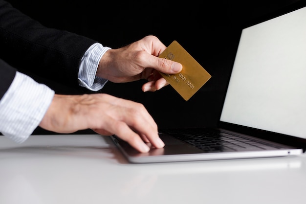 Hand using a card to buy online with laptop