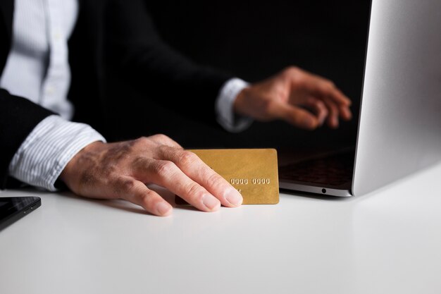 Hand using a card to buy online with laptop