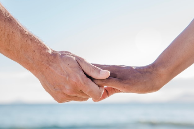 Hand view of couple at the beach