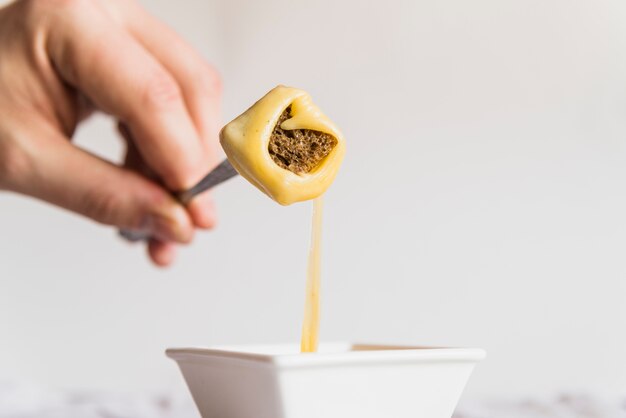 Hand with bread in cheese fondue on pick