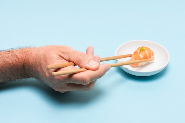 Hand with chopsticks eating sushi