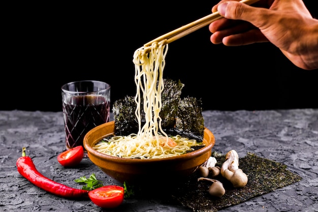 Hand with chopsticks and noodles soup