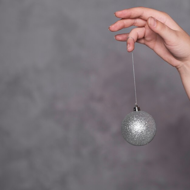 Hand with Christmas ball on thread