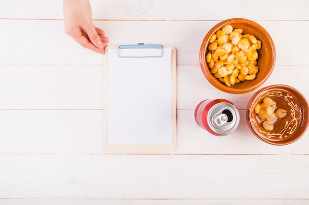 Free photo hand with clipboard and bean snack on table