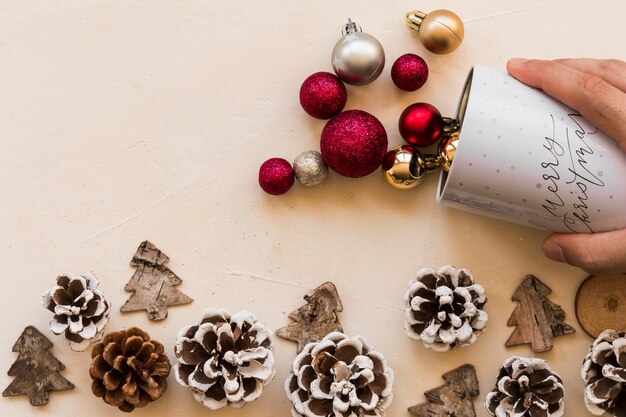 Hand with cup near ornament balls and snags 