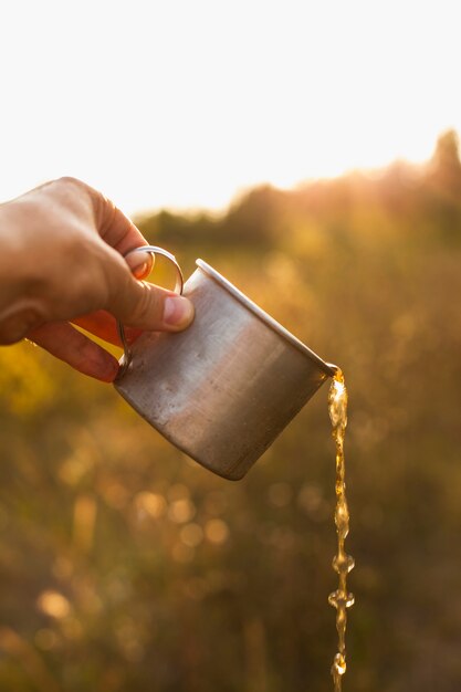 Hand with cup pouring drink 