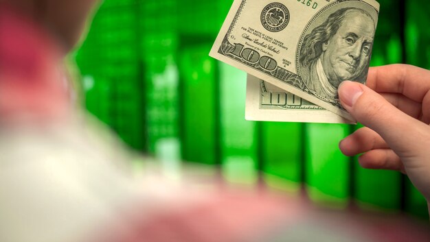 Hand with dollar bill. trading graph and green candlestick chart on a backgroud. financial investment, economy trends, business idea photo