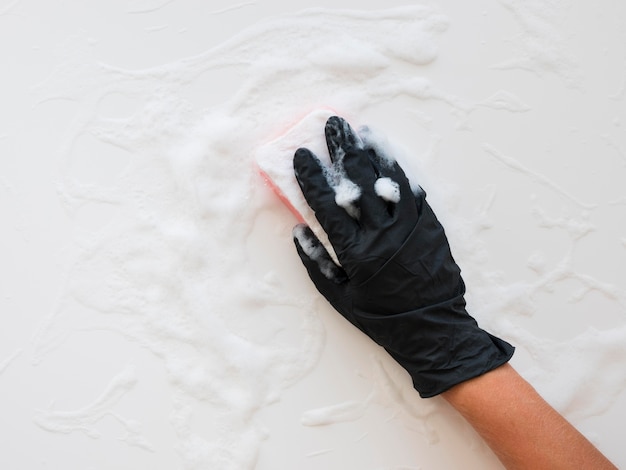 Hand with glove cleaning surface with sponge and foam