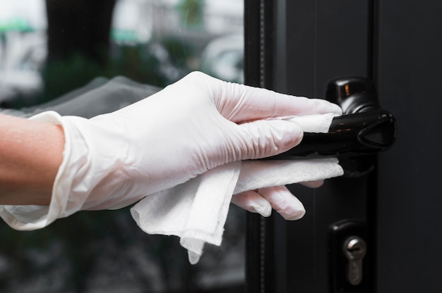 Hand with glove disinfecting door handle