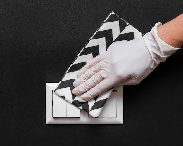 Hand with glove disinfecting light switches