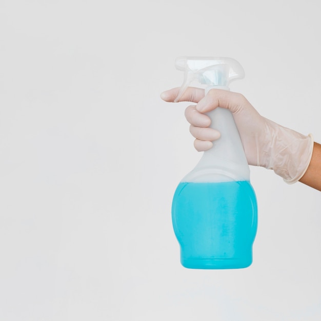 Hand with glove holding cleaning solution bottle