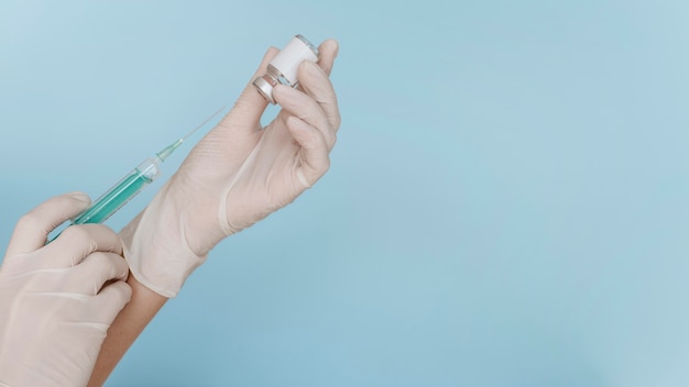 Hand with gloves holding a syringe with vaccine and copy space