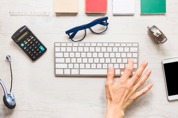 Hand with keypad and stationary on desktop