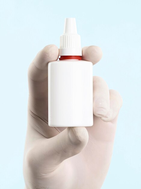 Hand with latex glove holding medicine bottle