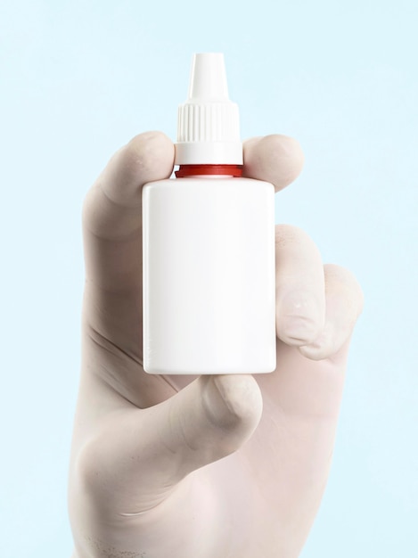 Hand with latex glove holding medicine bottle