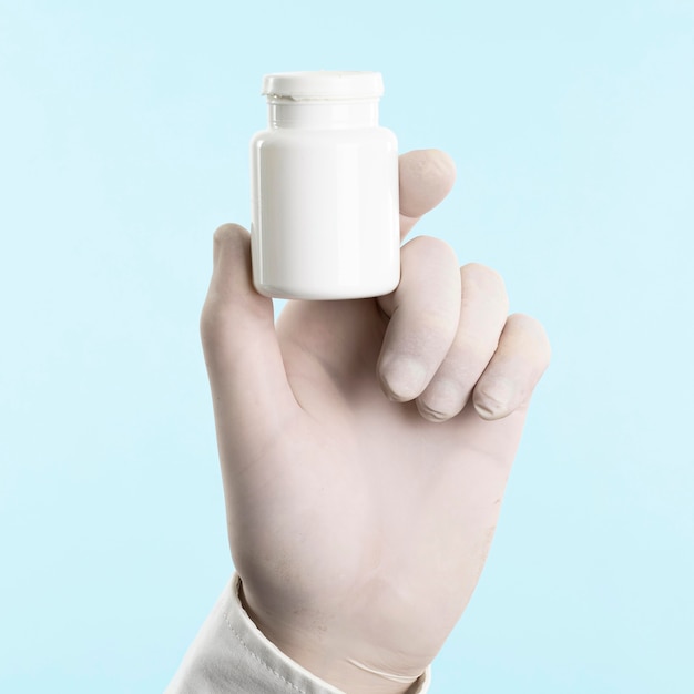 Hand with latex glove holding medicine bottle