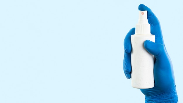 Hand with latex glove holding spray bottle with copy space