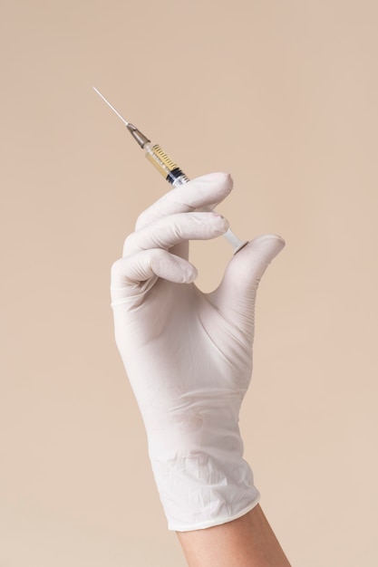 Hand with latex glove holding vaccine syringe