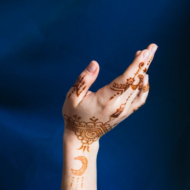 Hand with mehndi near blue textile