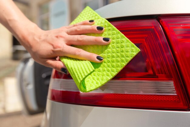 Hand with microfiber cloth cleaning car