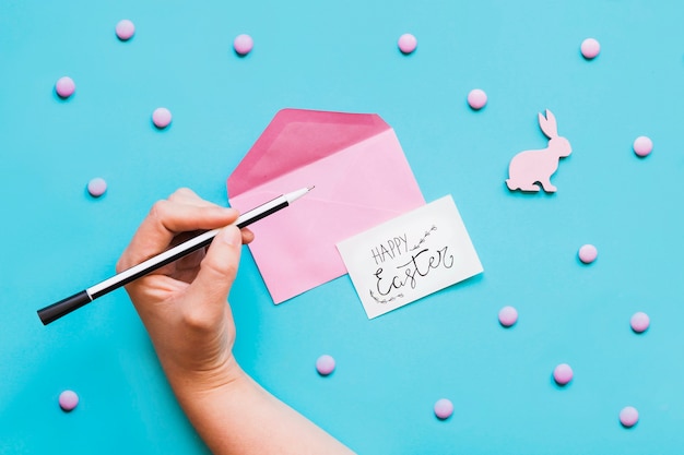 Hand with pen and envelope with greeting