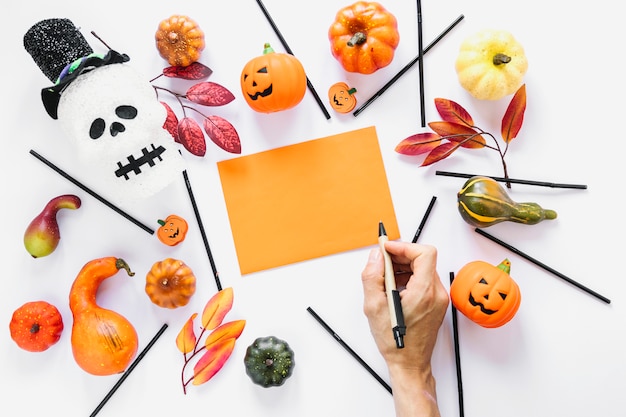 Hand with pen near piece of paper surrounded by decorations