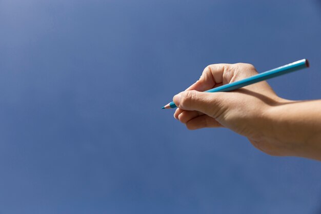 Hand with pencil to draw in the sky
