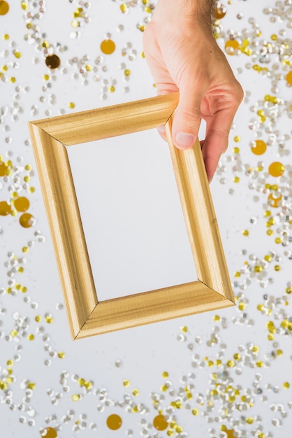 Hand with photo frame between colourful confetti