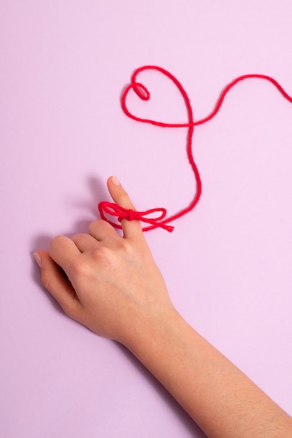 Hand with red thread in heart shape