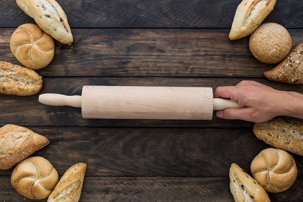 Free photo hand with rolling pin on desktop with bakery