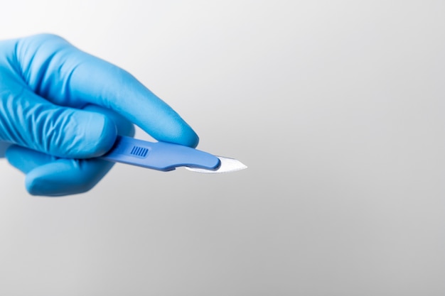 Hand with rubber glove holding medical scalpel