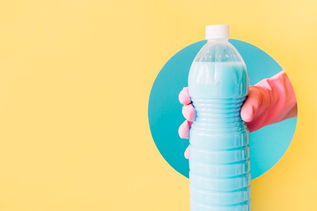 Hand with rubber gloves holding plastic bottle