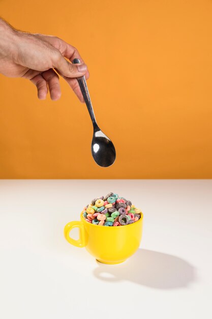 Hand with spoon to mix bowl with milk and cereals