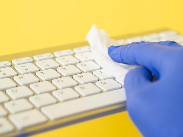 Hand with surgical glove disinfecting keyboard