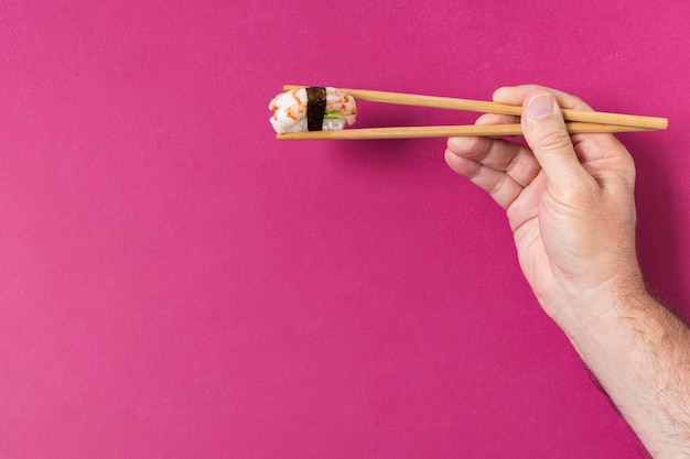 Hand with sushi on chopsticks