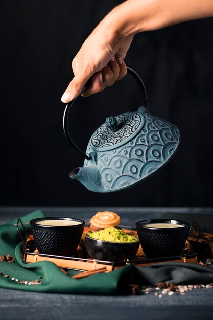 Hand with teapot pouring drink in cup