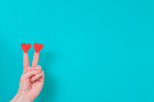 Hand with two fingers with two hearts on a blue background